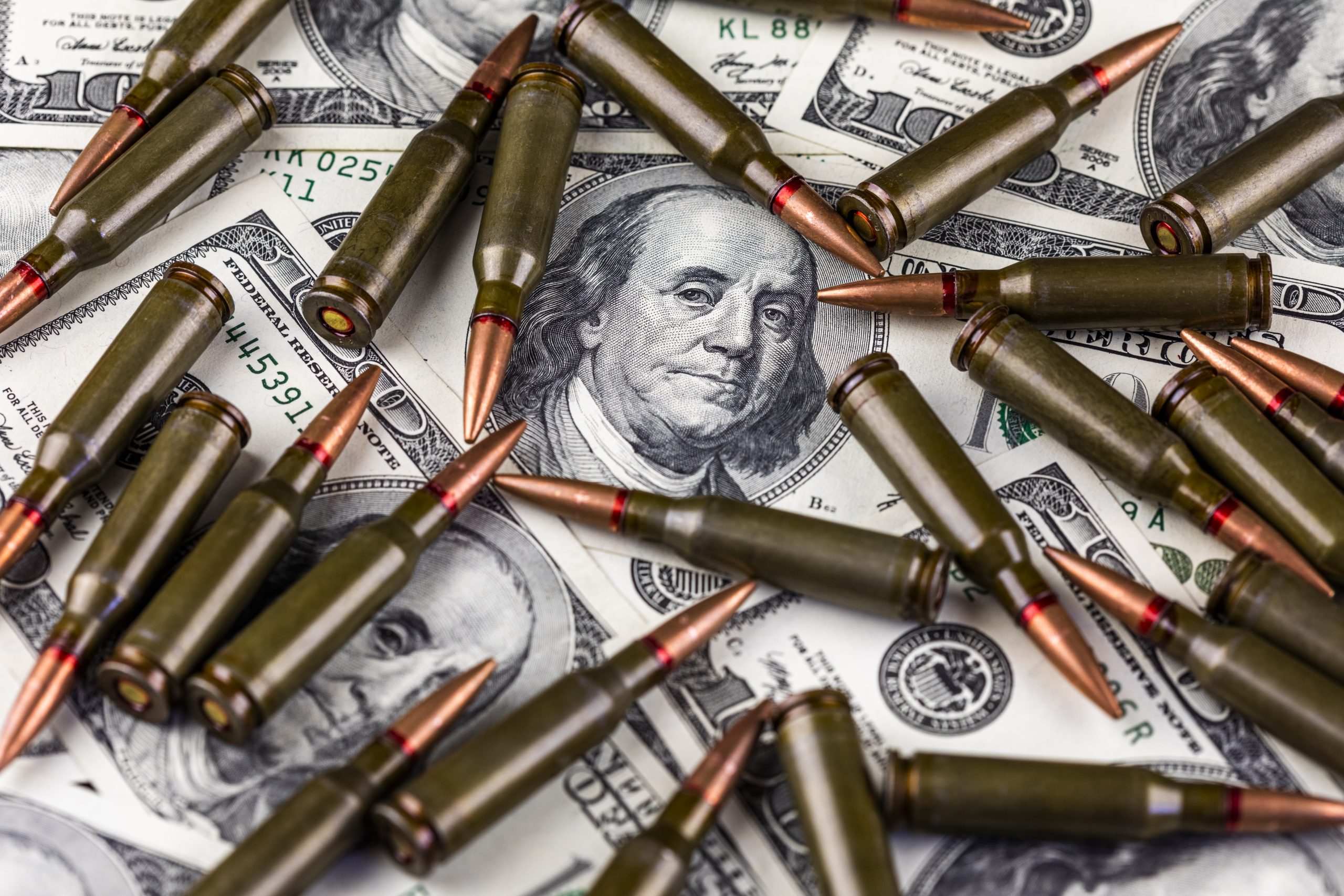 Hundred dollar bills and machine gun cartridges. Concept of economic crisis due to war
